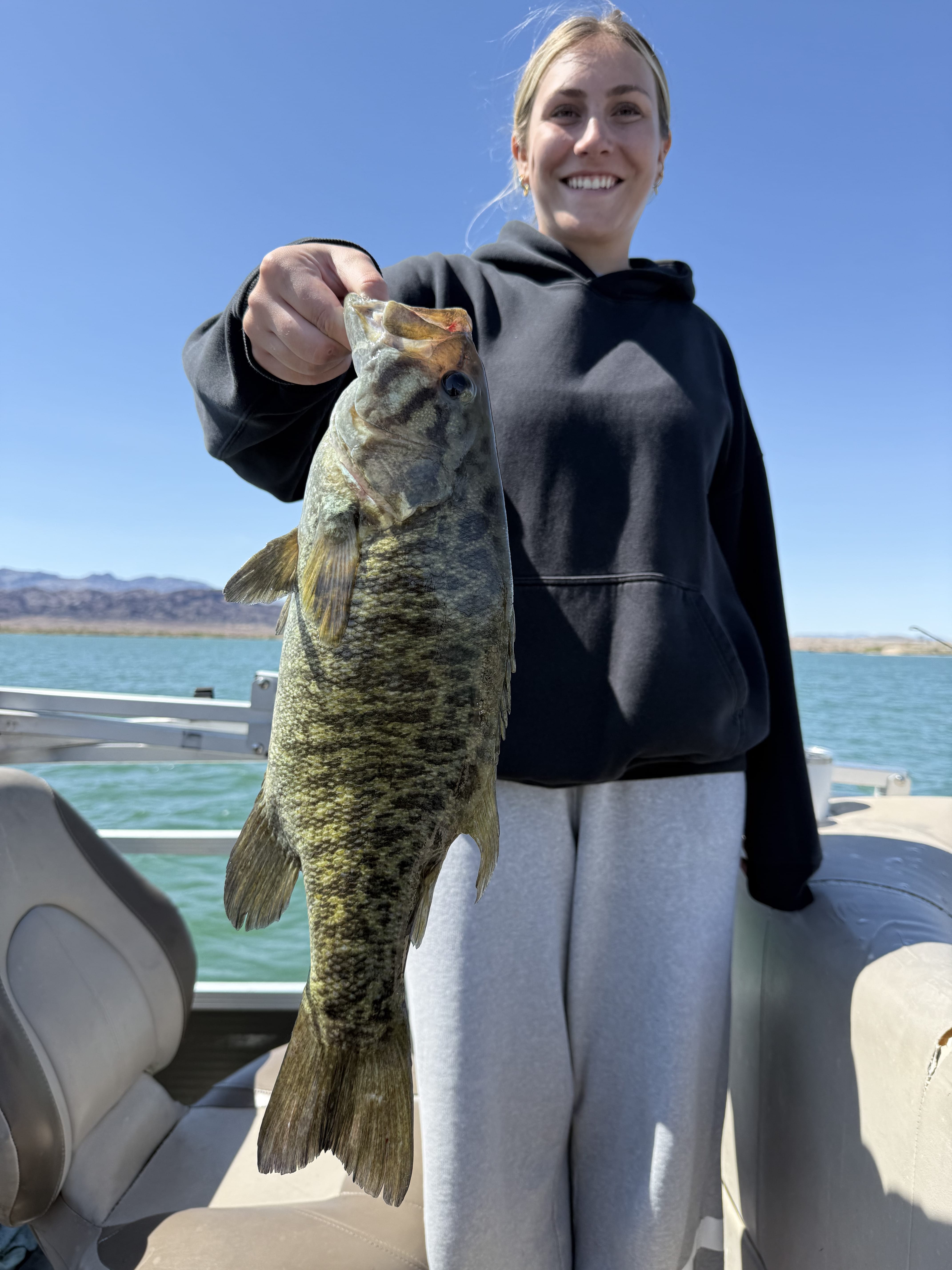 Angler holding a smallmouth or spotted bass on the boat