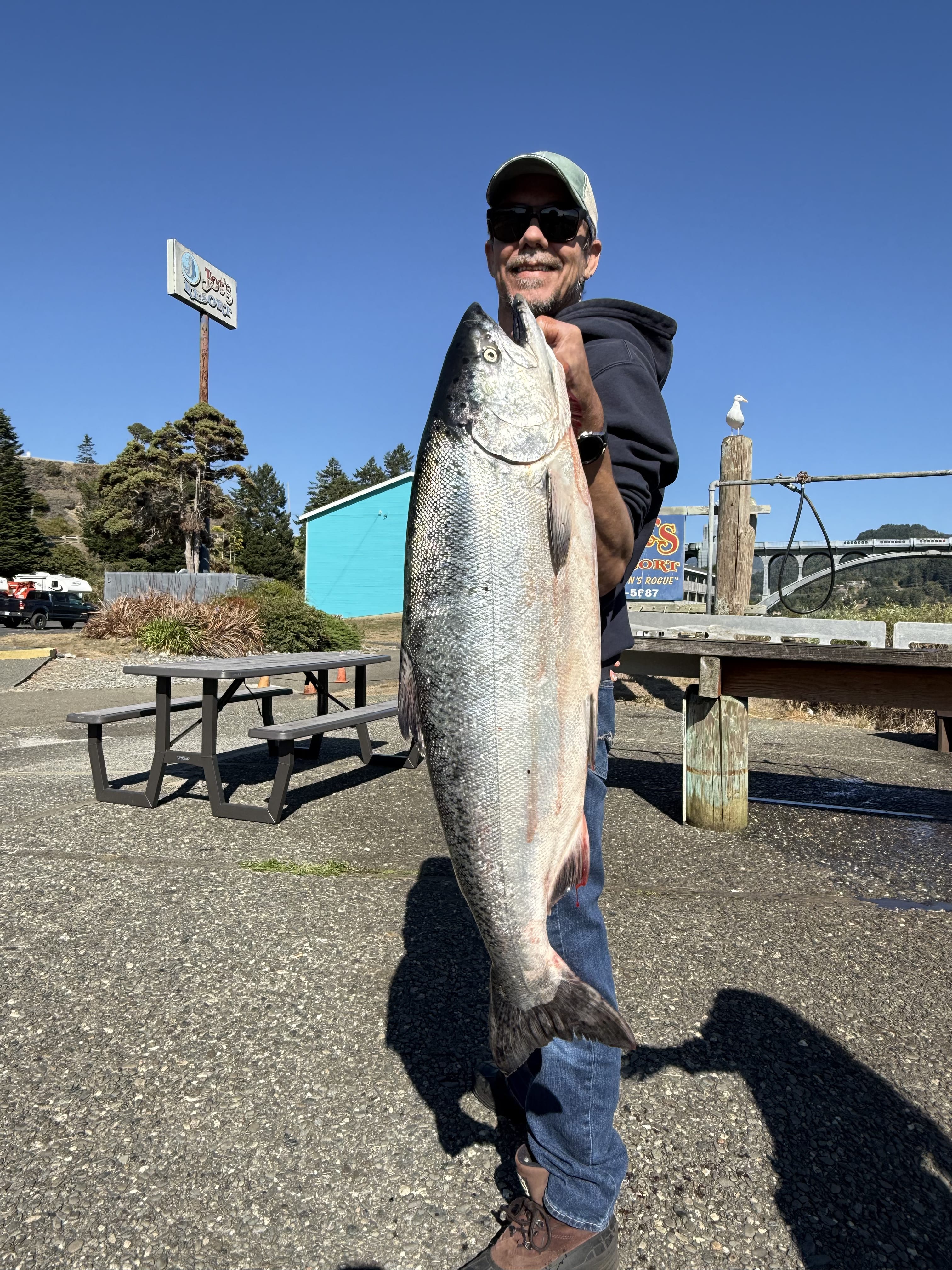 Angler holding a striped bass along rocky shoreline