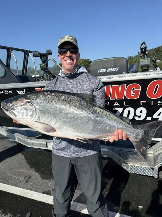 Angler holding a Chinook salmon beside the guide boat